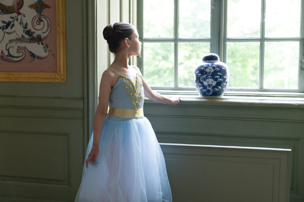 Little ballerina in costumes watching outside de window